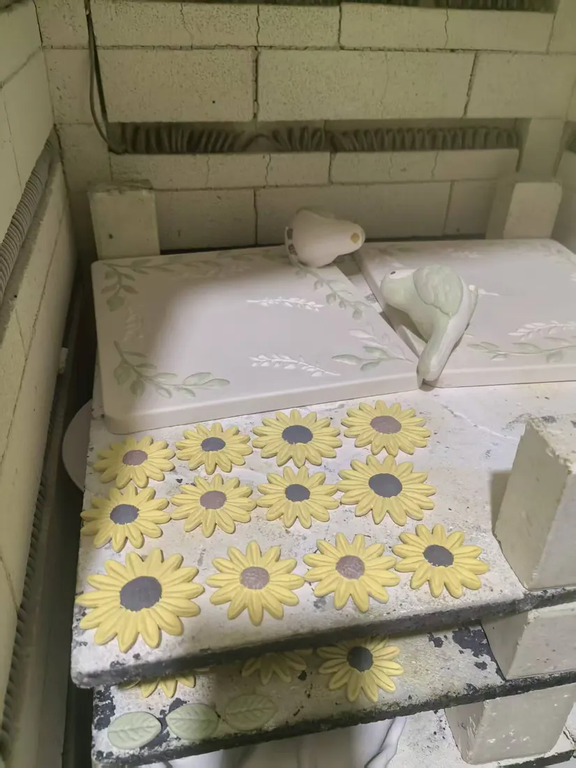 Ceramic plaques with relief and bird figurines in the kiln before firing