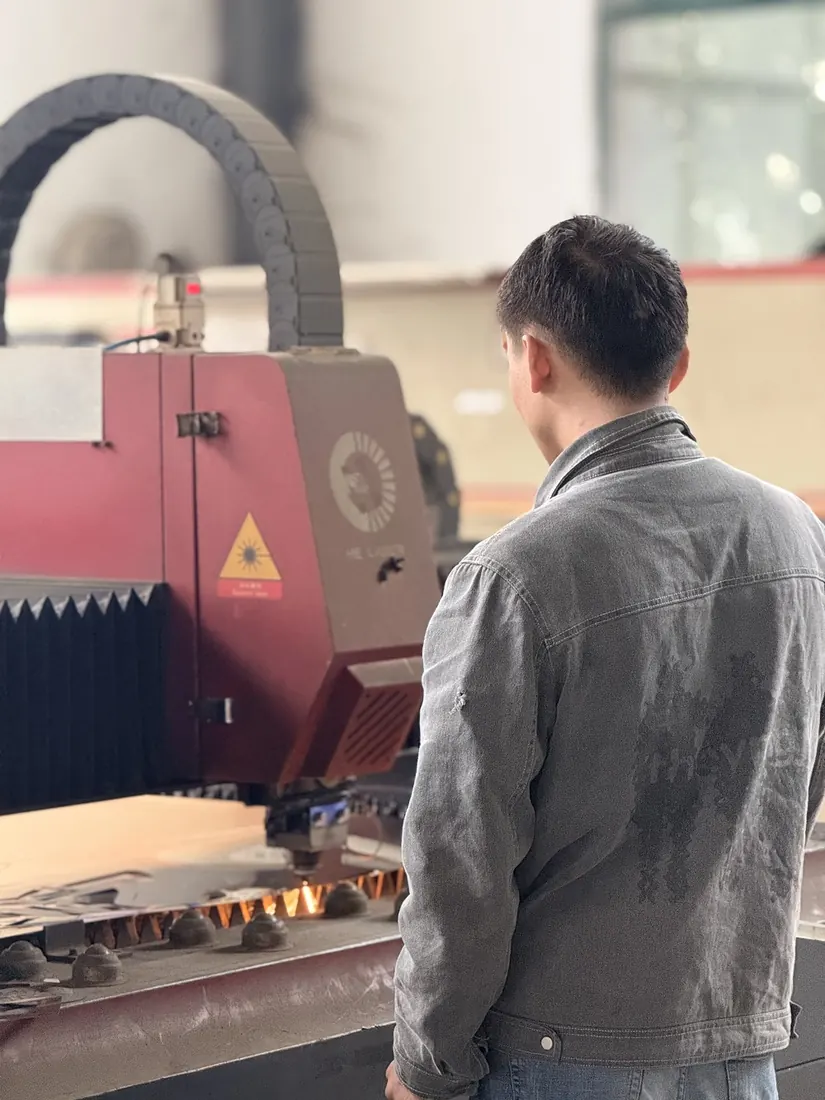 Worker operating a laser cutting machine on sheet metal
