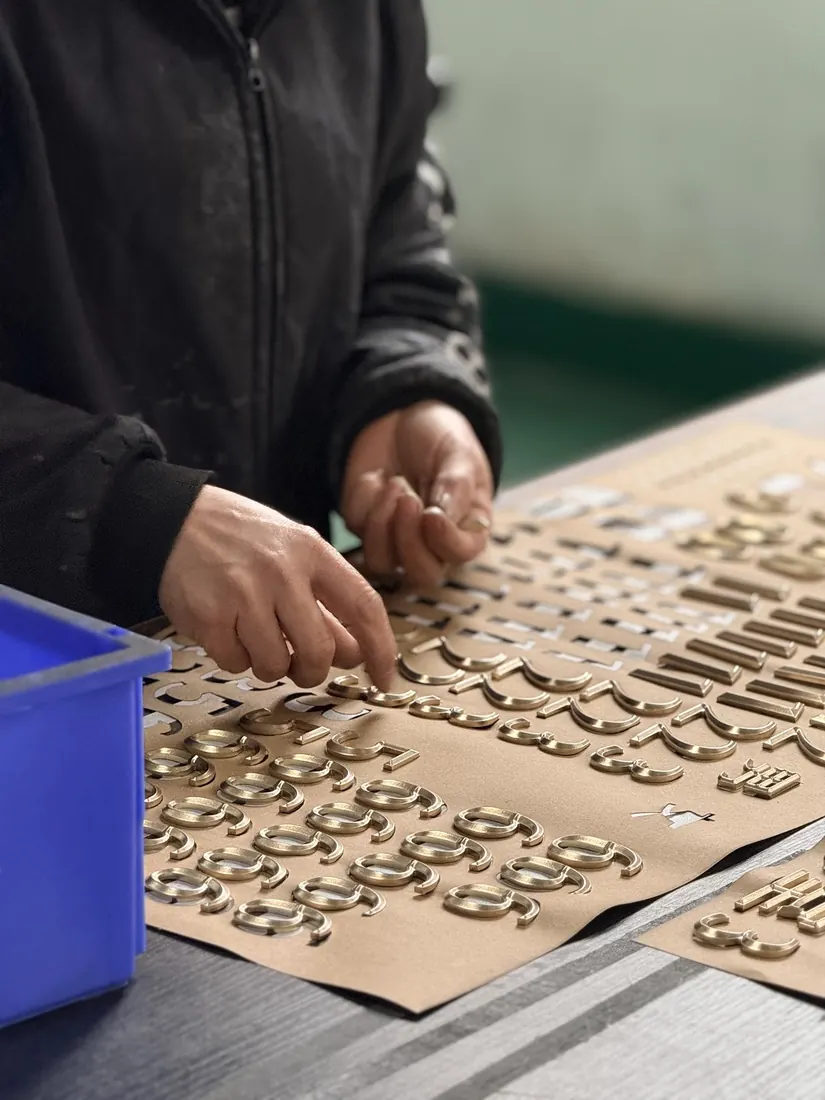 Worker aligning dimensional letters before assembly