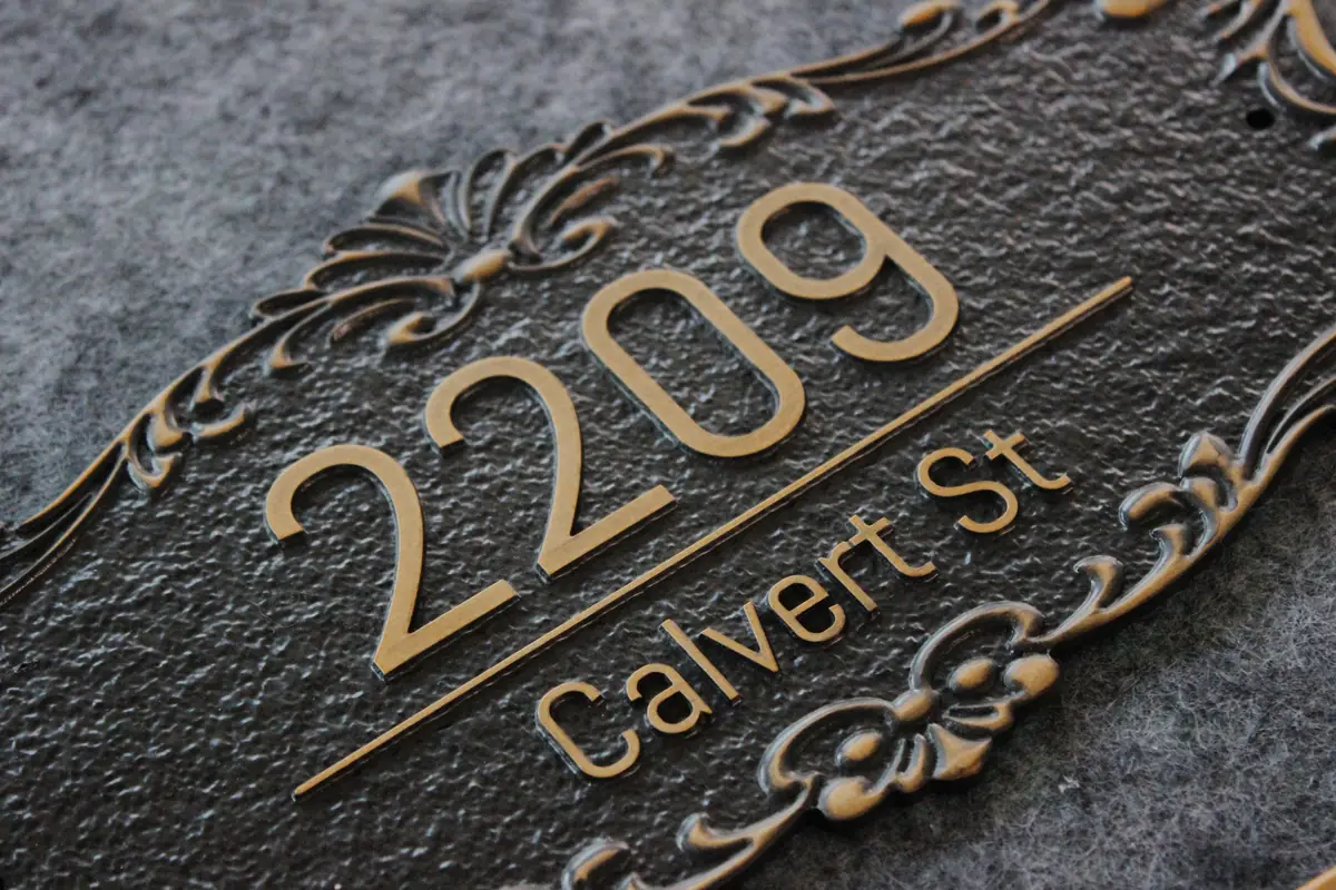 CNC-carved aluminum plaque with aged brass raised numbers and dark textured background