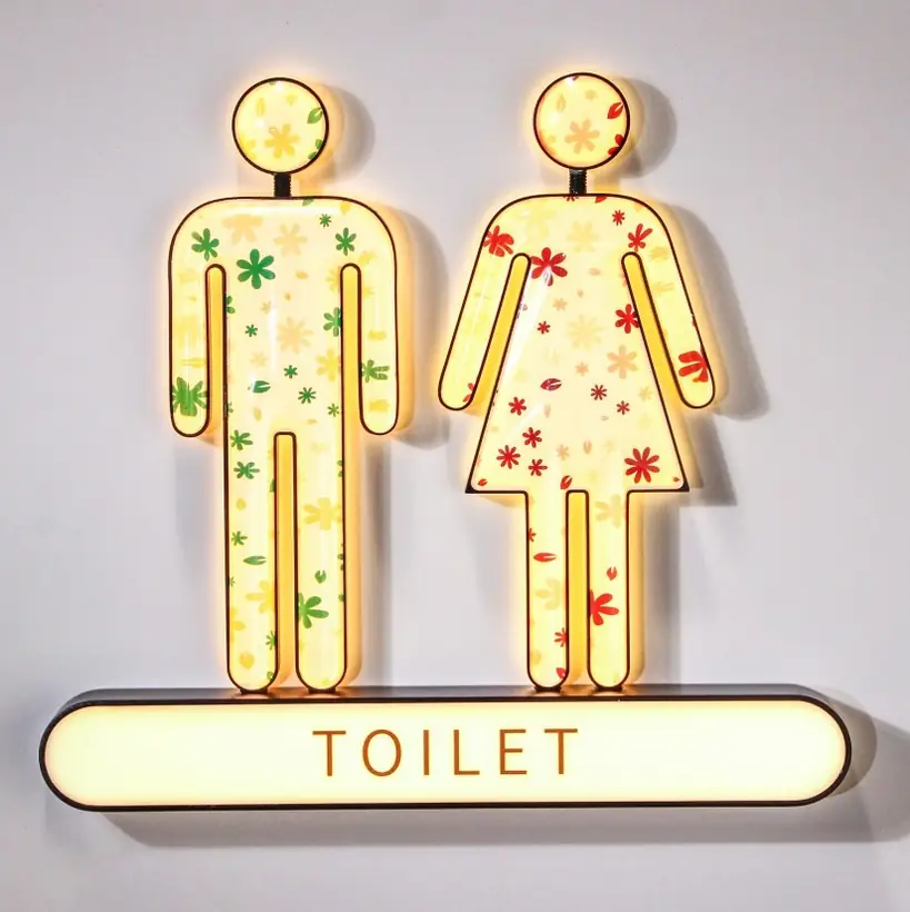Illuminated restroom sign with colorful figures